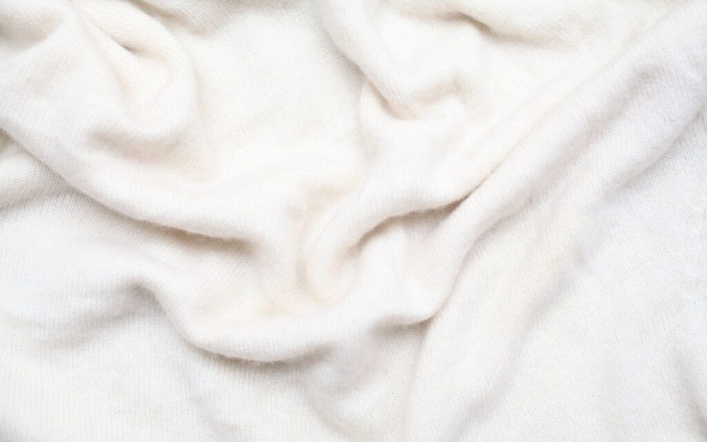 Soft, draped, off-white knit fabric texture.
