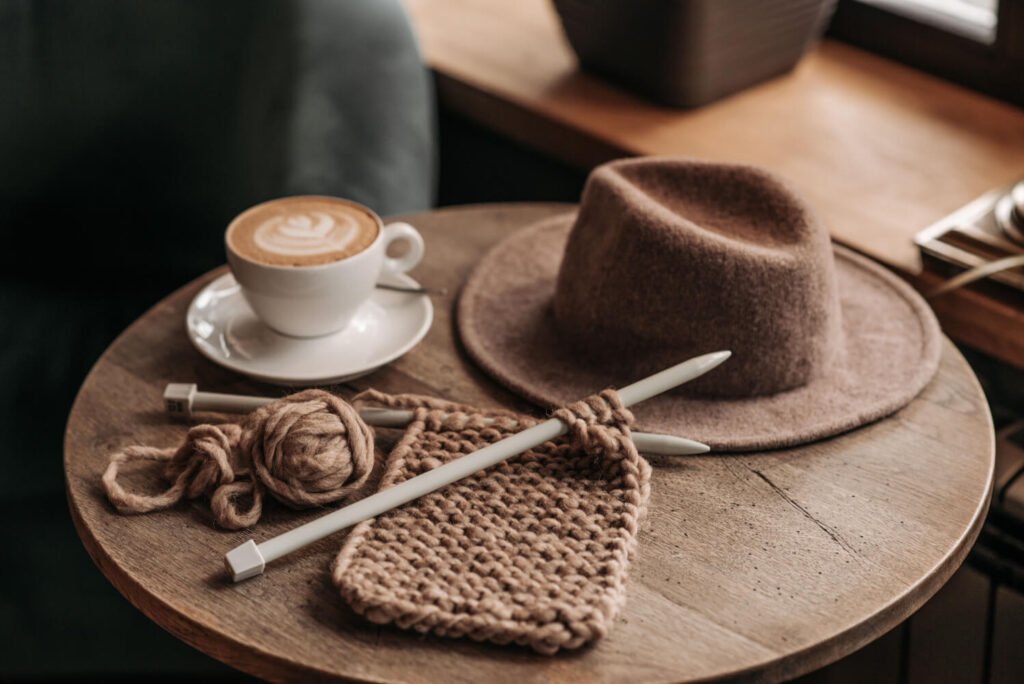 Cozy knitting project, coffee, and hat on wooden table.