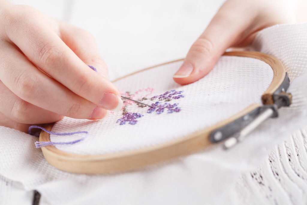 Hands, needle and thread, cross stitch, embroidery.