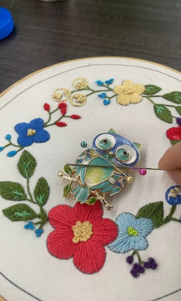 Embroidered owl brooch on floral fabric hoop.