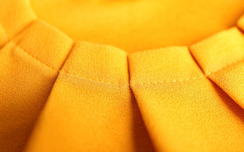 Closeup of pleated, golden yellow fabric.